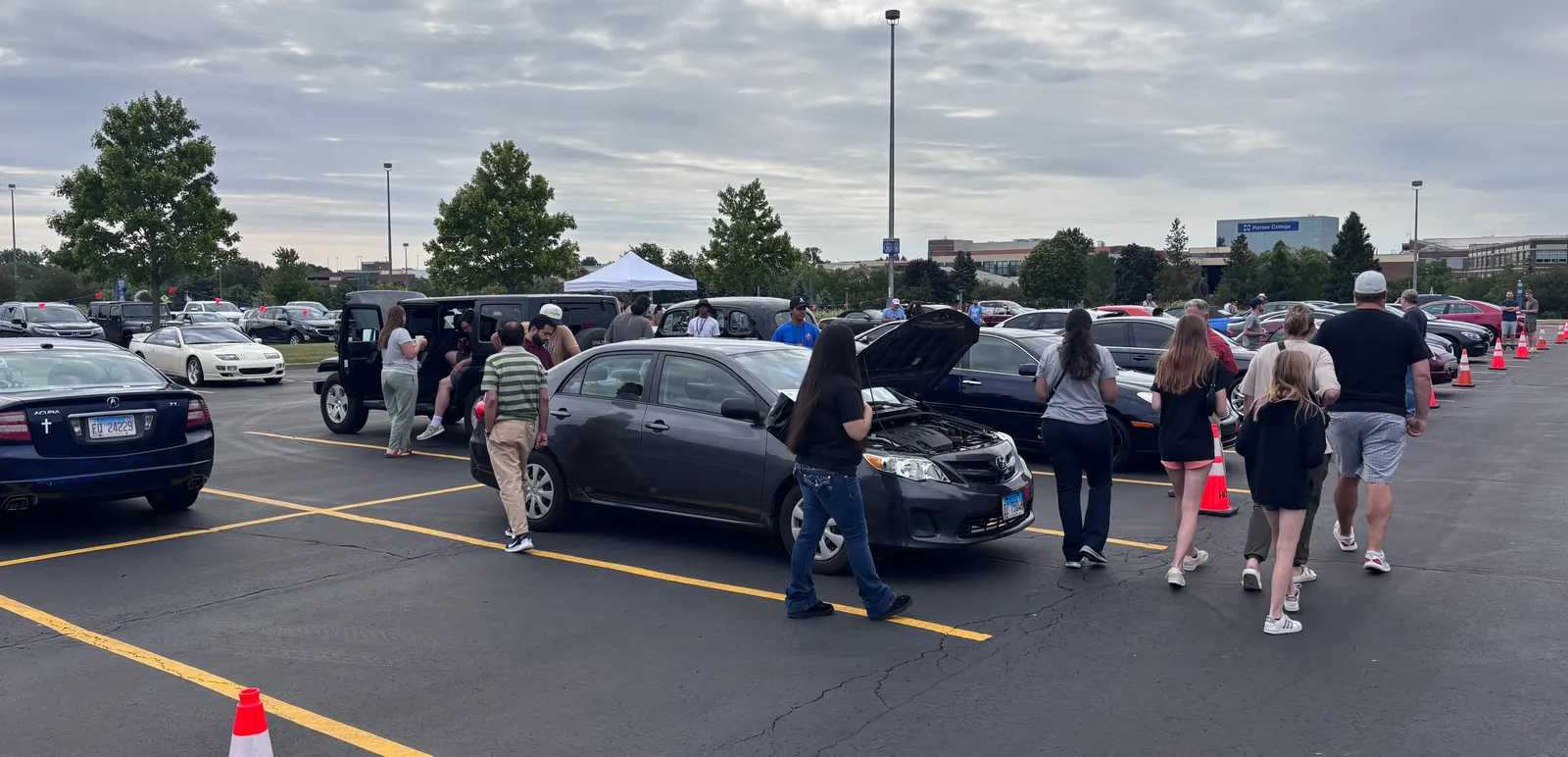 Buyers walking the lot inspecting cars at a Chicagoland Auto Fair event at Harper College