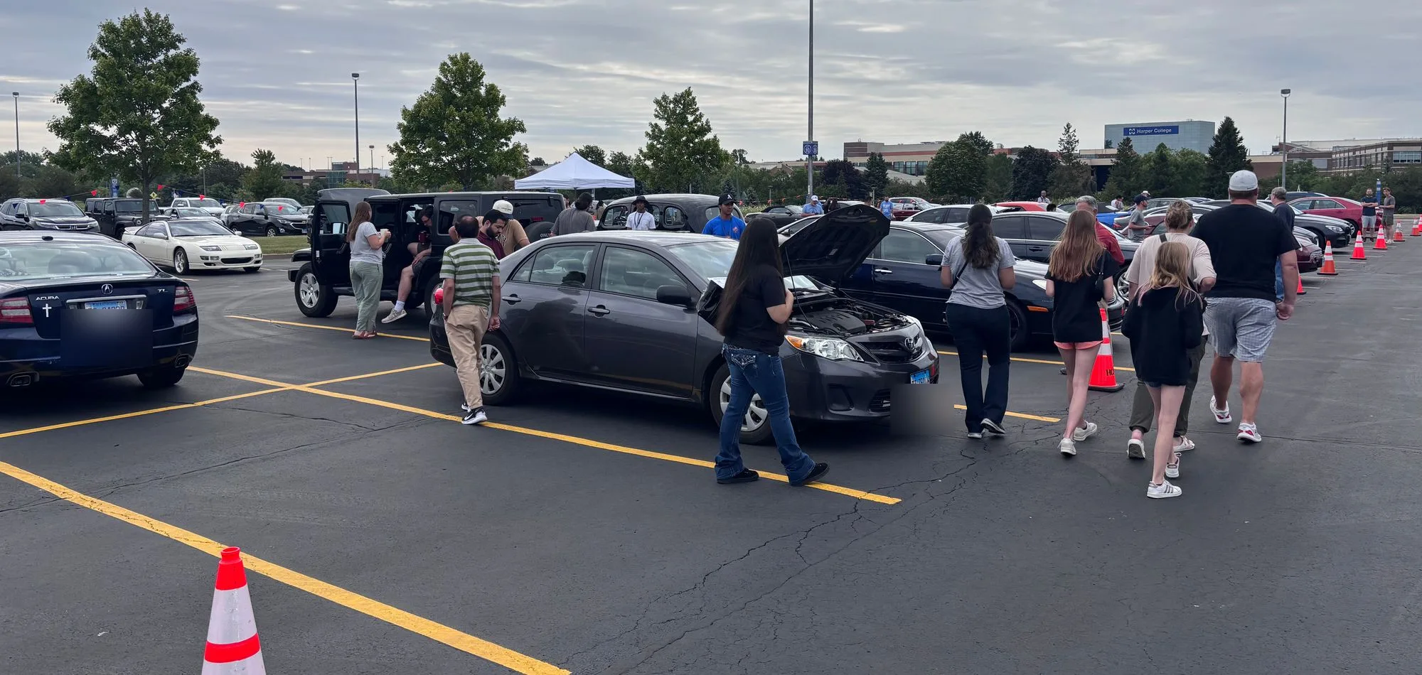 A crowd of buyers looking at cars on the lot