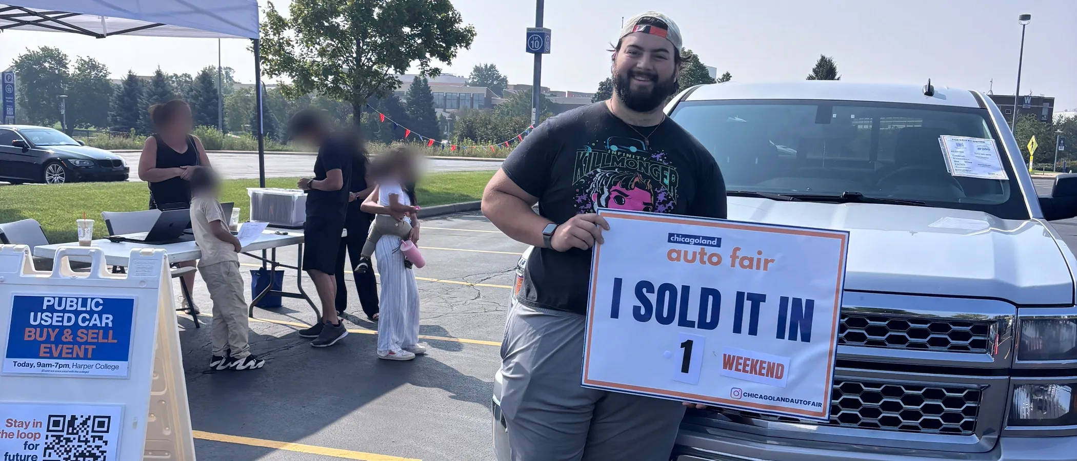 A seller holding an I sold it in 1 weekend sign beside his Chevrolet Silverado at the Chicagoland Auto Fair check-in tent