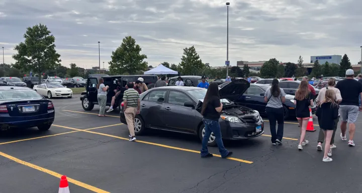 Buyers walking between rows of cars on the lot at the Auto Fair