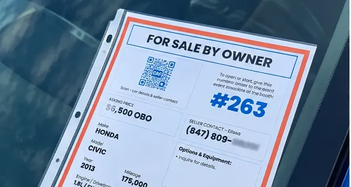 A For Sale By Owner window sticker on a windshield showing the key number, asking price, and the owner's phone number