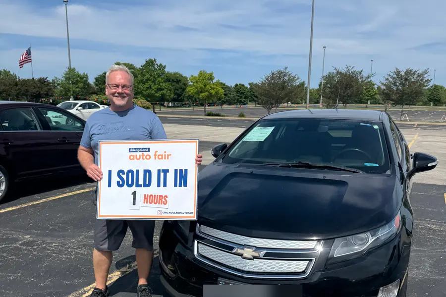 A seller standing with his Chevrolet Volt and a Chicagoland Auto Fair sold sign at Event #1