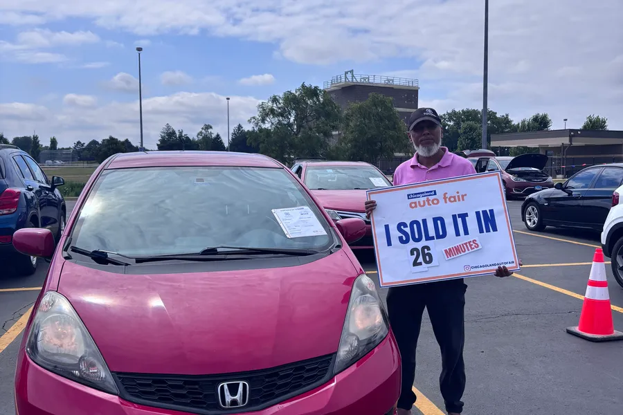 A seller holding an I sold it in 26 minutes sign with their Honda Fit