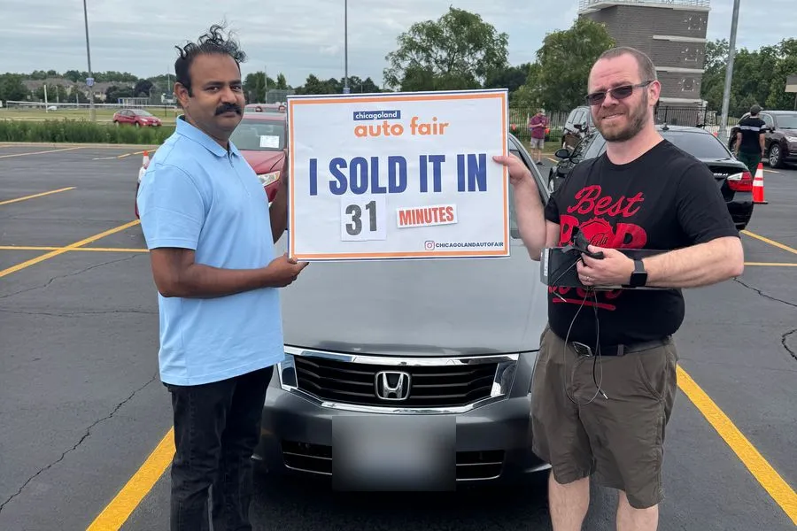 A seller and his buyer holding an I sold it in 31 minutes sign with a Honda Odyssey
