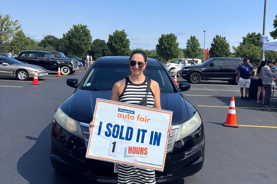 A seller holding an I sold it in 1 hour sign with her Honda Crosstour