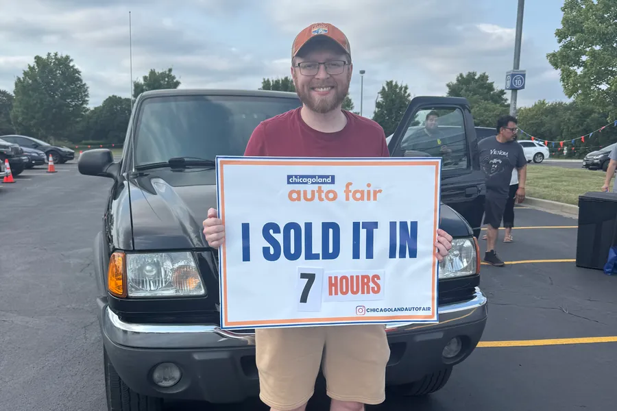 A seller holding an I sold it in 7 hours sign with his Ford Ranger