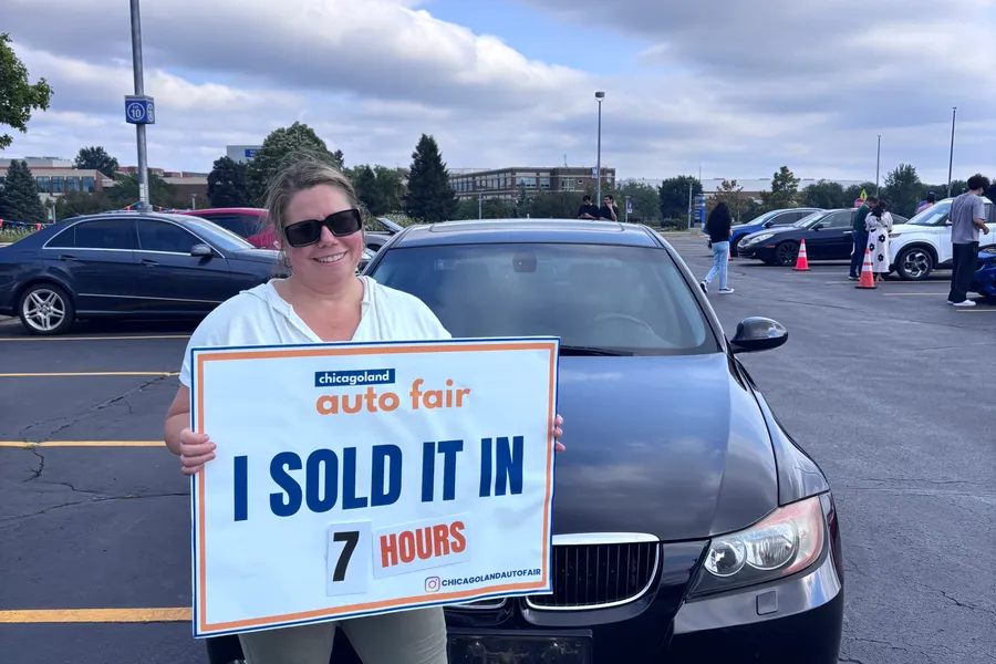 A seller holding an I sold it in 7 hours sign with her BMW 3 Series
