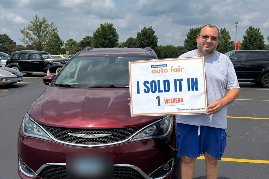 A seller holding an I sold it in 1 weekend sign with his Chrysler Pacifica
